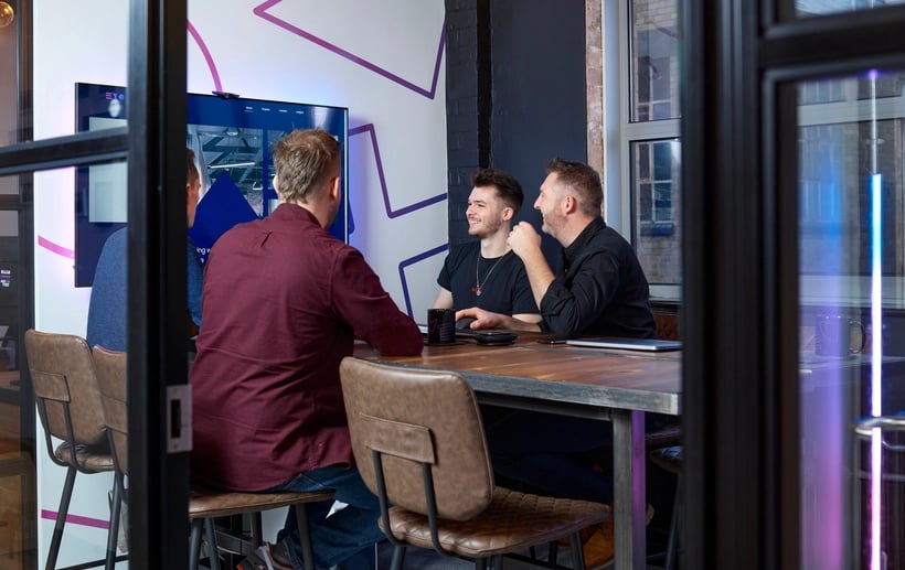 A close-up of two Evo Agency employees sitting together at a table laughing and smiling.