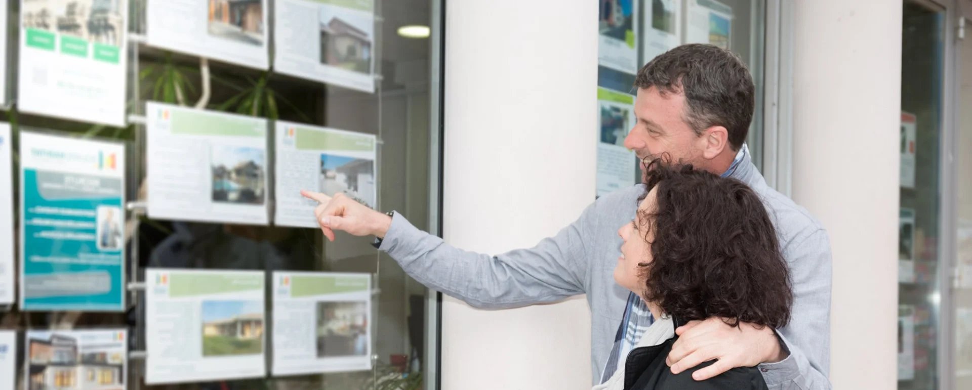 Couple looking at house listings in shop